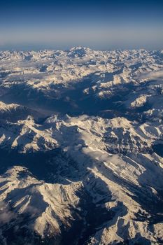 Swiss Alpes with snowy mountain tops aerial view towards the east during afternoon flight in December