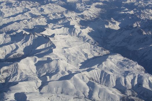 Swiss Alpes with snowy mountain tops aerial view towards the east during afternoon flight in December