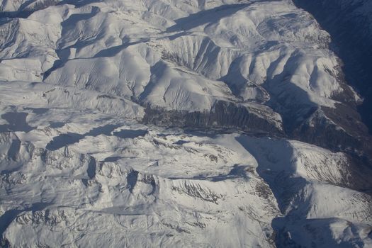 Swiss Alpes with snowy mountain tops aerial view towards the east during afternoon flight in December