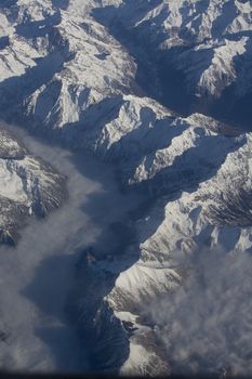 Swiss Alpes with snowy mountain tops aerial view towards the east during afternoon flight in December