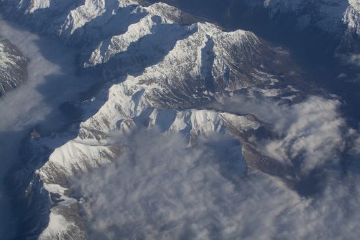 Swiss Alpes with snowy mountain tops aerial view towards the east during afternoon flight in December