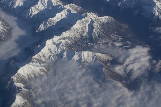 Swiss Alpes with snowy mountain tops aerial view towards the east during afternoon flight in December