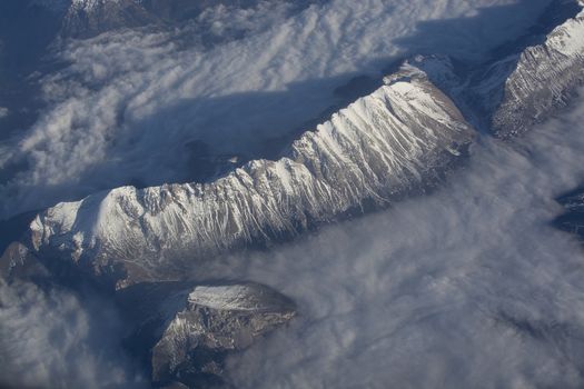 Swiss Alpes with snowy mountain tops aerial view towards the east during afternoon flight in December