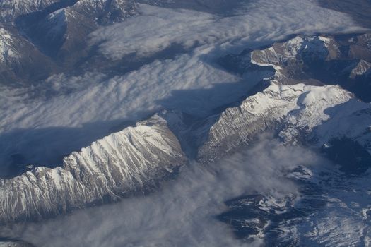 Swiss Alpes with snowy mountain tops aerial view towards the east during afternoon flight in December