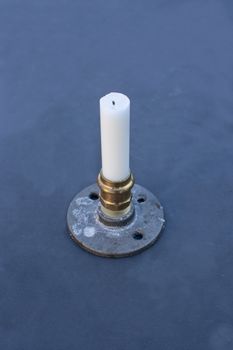 Plumber candle holder. Candle holder created from plumbing parts on dark table.