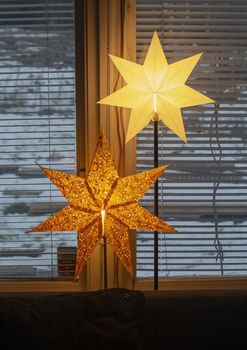 Advent star christmas decorations in window with snow outside in the afternoon in Stockholm, Sweden.