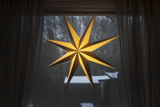 Advent star christmas decorations in window with snow outside in the afternoon in Stockholm, Sweden.