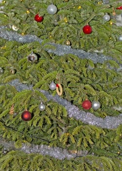 Fresh green Christmas tree decorated with glitter silver and red ornaments