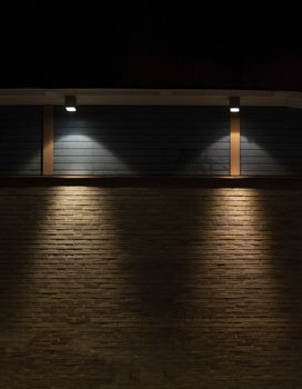 Brick and wood wall background in darkness with lights in triangular shape