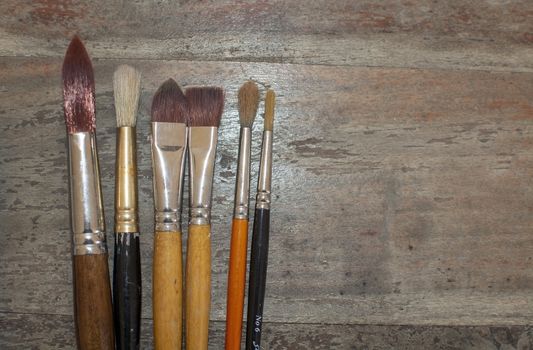 Set of various artist brushes for watercolor painting on old shabby grungy retro vintage wooden background.