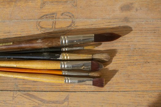 Set of various artist brushes for watercolor painting on old shabby grungy retro vintage wooden background.