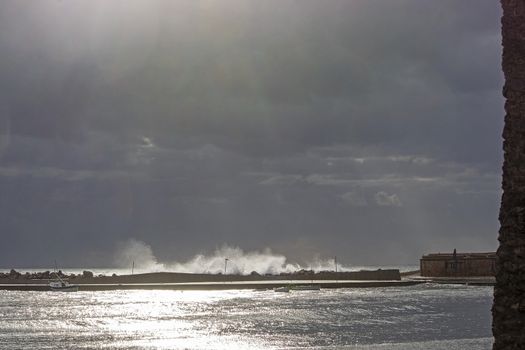 Mediterranean sea view with pier against dark skies with dramatic light on a winter day in Mallorca, Spain.