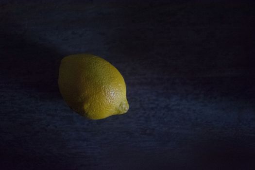 Lemon in darkness almost looking like a planet, with chiaroscuro lighting
