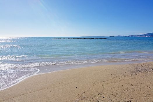 Untouched sand beach with wave residue pattern and blue sea in Mallorca, Spain.