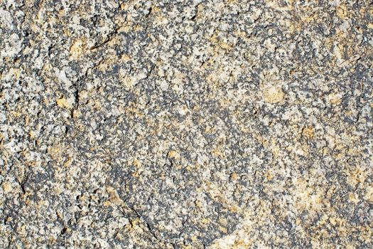 Granite surface texture closeup background shows large crystals of brown feldspar, quartz and black biotite.