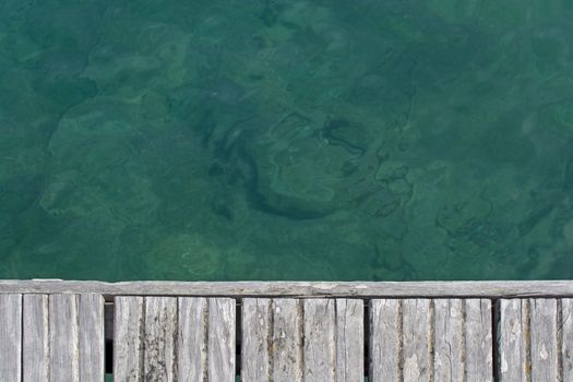 Emerald green water and wood boardwalk background texture, Sardinia, Italy.