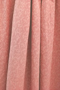 Beautiful folded damask woven cotton fabric background texture vertical toned in trend color Living Coral.