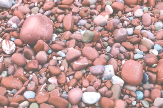 Stones rounded by waves toned in Living Coral shades background texture