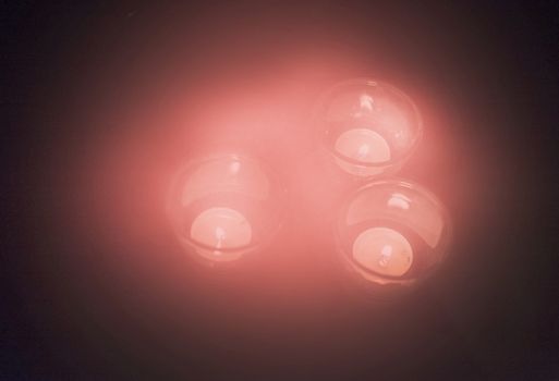 Candles in hazy coral color light up darkness with copy space.