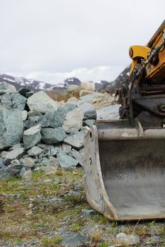 Excavator bucket moving stones in mountains close-up