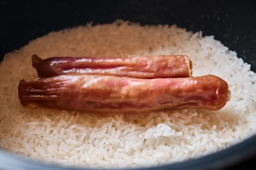 Two chinese pork sausage cooked in a rice cooker with rice.