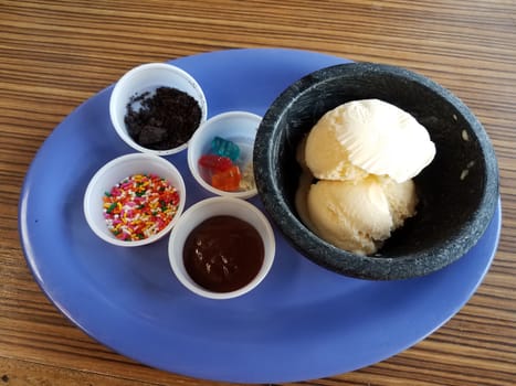 vanilla ice cream with sprinkles and chocolate on blue plate on wood table