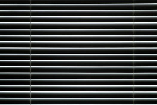 Closed window blinds. Light makes its way through closed blinds.