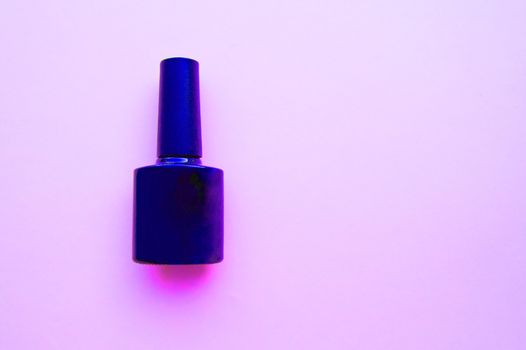 One bottle of nail Polish with neon light on pink background, place for promotional test, layout for beauty blog.