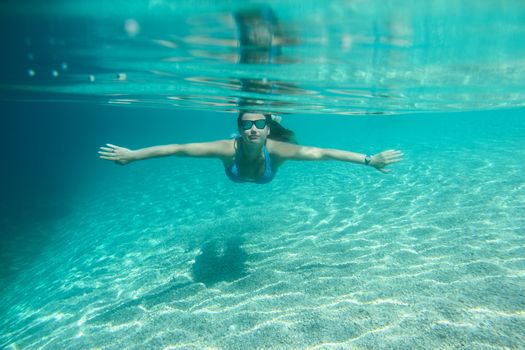 Woman in sunglasses diving on a breath hold swimming under water view