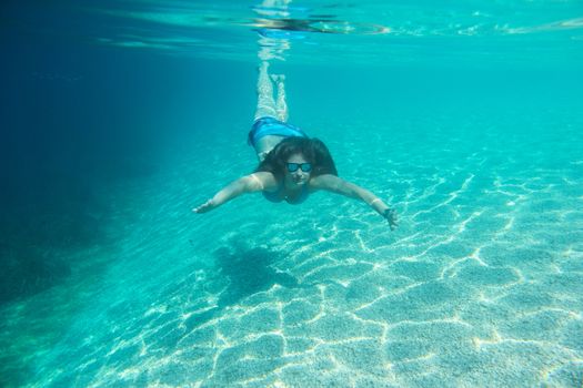 Woman in sunglasses diving on a breath hold swimming under water view