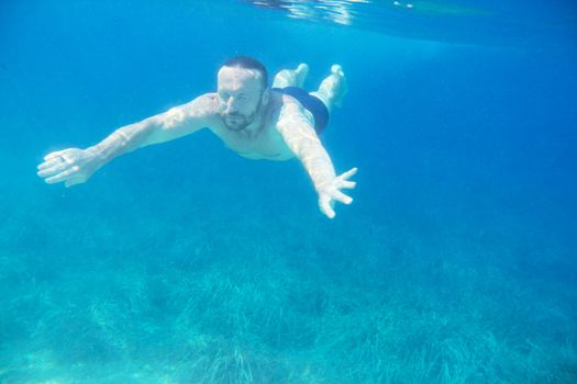 Bearded man diving on a breath hold swimming under water view