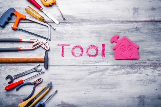 Set of work tool on rustic wooden background with house icon and written "tool" in space, industry engineer tool concept.still-life.