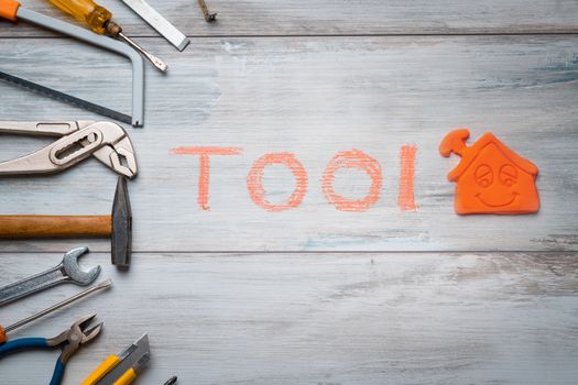 Set of work tool on rustic wooden background with house icon and written "tool" in space, industry engineer tool concept.still-life.