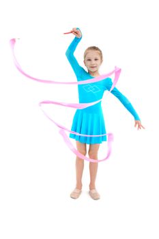 Young girl gymnast exercising with pink ribbon on white studio background