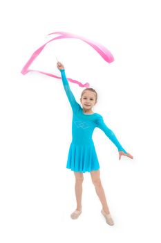 Young girl gymnast exercising with pink ribbon on white studio background
