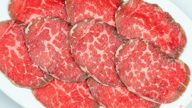 Top view of some raw beef on a plate over white background