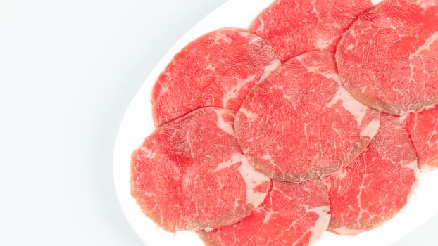 Top view of some raw beef on a plate over white background