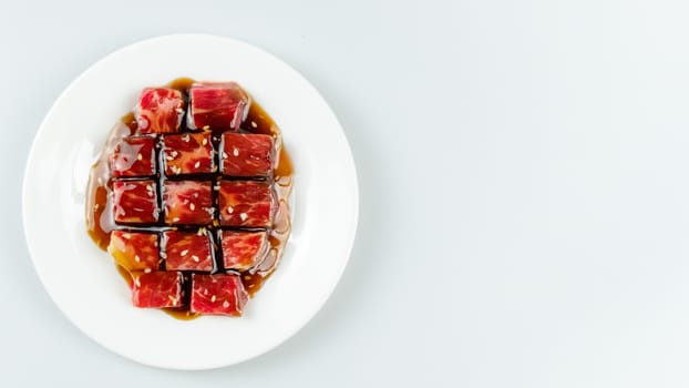 Top view of some raw beef with sauce on a plate over white background