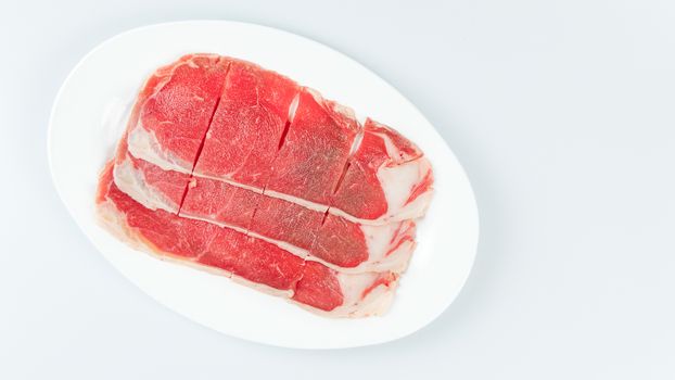 Top view of some raw beef on a plate over white background