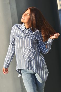 Portrait's young cool asian girl stands near the wall and posing and she dressed a striped shirt