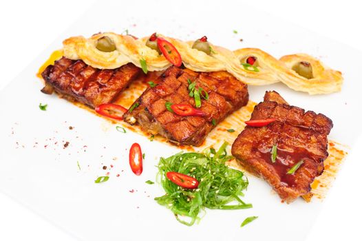 grilled pork ribs with bread pigtail and seaweed, served on plate, isolated on white
