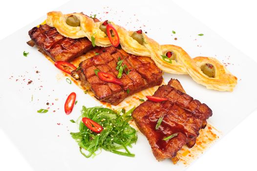 grilled pork ribs with bread pigtail and seaweed, served on plate, isolated on white