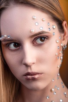 Portrait of a girl with original and creative makeup with white and pearl rhinestones