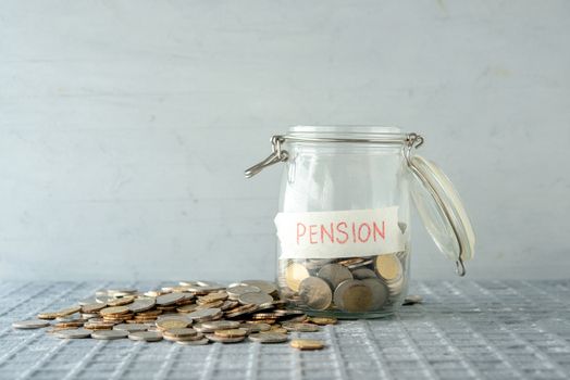 Coins in glass money jar with pension label, financial concept. 