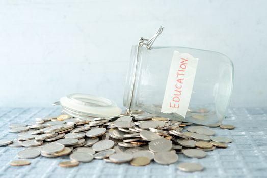 Coins and glass money jar with education label, financial concept.