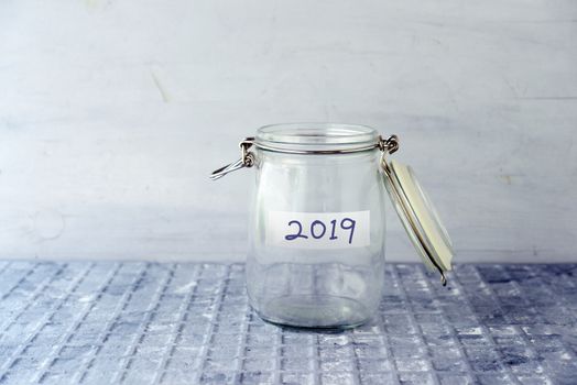 Empty glass money jar with 2019 label, financial concept.