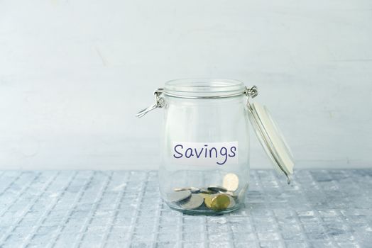 Coins in glass money jar with savings label, financial concept.