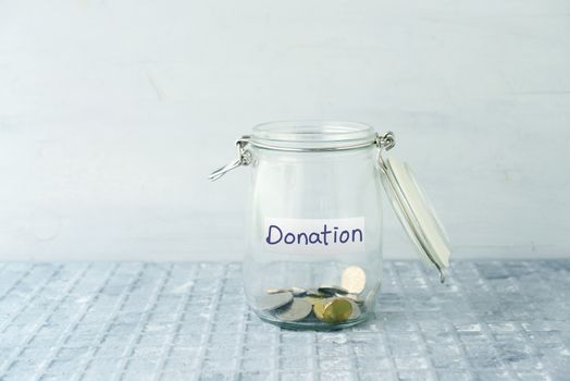 Coins in glass money jar with donations label, financial concept.
