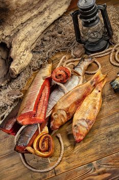 Different kinds of smoked fish and fushing net on a wooden desk