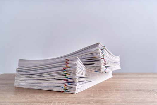 Pile overload paperwork of report with colorful paperclip place on wood table and white background with copy space. Business and finance concepts successful photography.